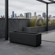 Rooftop terrace | empty matte charcoal-black composite trough planter in a cool slate-paved garden