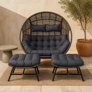 Patio hero | Complete dark-brown woven double egg chair set with two charcoal-cushioned ottomans on a warm plaster patio