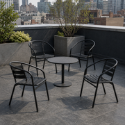 In a room | four black stacking patio armchairs around a round table on a slate city roof terrace