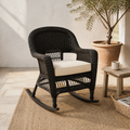 Mediterranean porch | espresso resin-wicker rocking chair with pale tan seat cushion, olive tree, rug, and wood table
