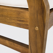 Close view | Round brass-toned chair-frame fastener set into warm-brown acacia above a side stretcher