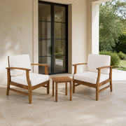 Scale | Two acacia club chairs and a slatted side table beside a full-height exterior doorway