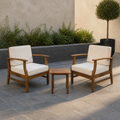 Room | Two warm-brown acacia club chairs with cream cushions and one slatted side table in a cool bluestone courtyard