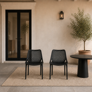 Scale view | Two Black stacking chairs beside a full-height exterior doorway