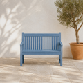 In a room | blue slatted poly lumber garden bench on a limestone terrace beside an olive planter