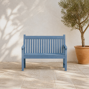 In a room | blue slatted poly lumber garden bench on a limestone terrace beside an olive planter
