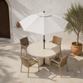 Mediterranean courtyard angle | open off-white octagonal umbrella from above over a round patio table with four woven chairs