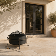 Scale view | Dark steel cauldron fire pit beside a full-height exterior doorway