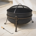Low terrace three-quarter | Dark steel cauldron fire pit with mesh screen, curled legs, and poker