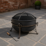 Red brick courtyard | Dark steel cauldron fire pit with mesh spark screen and wood-handled poker