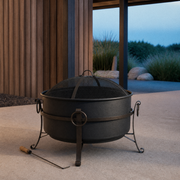 Coastal patio | Dark steel cauldron fire pit with mesh spark screen and wood-handled poker