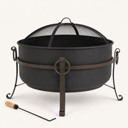 Studio front | Dark steel cauldron fire pit with mesh spark screen, ring latch, three curled legs, and poker