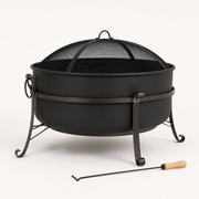 Studio side | Dark steel cauldron fire pit showing bowl profile, mesh screen, side handle, curled legs, and poker