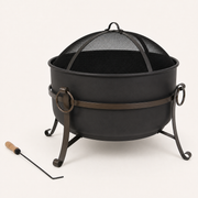 Studio three-quarter | Dark steel cauldron fire pit with muted dark bronze band, mesh screen, curled legs, and poker