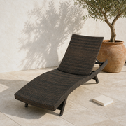 In a room | dark Mix Mocha wicker chaise lounge on a limestone terrace beside an olive tree