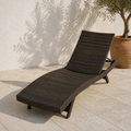 Angle | low three-quarter terrace view of the dark wicker chaise with olive tree behind