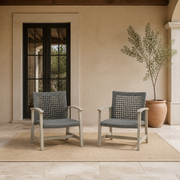 Scale view | Two light gray-washed acacia and dark wicker club chairs beside a full-height glass doorway