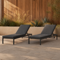 Courtyard | Two dark gray reclining chaise lounges on clay pavers in front of a cedar screen