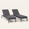 Studio front | Two dark gray reclining chaise lounges with raised backs on a warm white ground