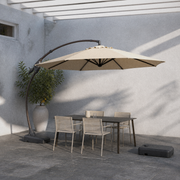 In a room | cool slate courtyard with Sand offset cantilever umbrella over a dark table and chairs, separate wheeled base at right