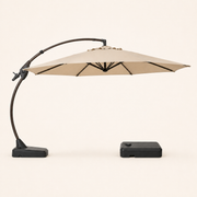Side | side studio profile of open Sand cantilever umbrella, curved arm, mast foot, and separate wheeled base