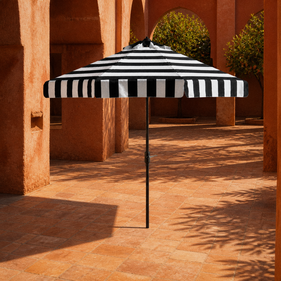 In a room | open black and white striped umbrella in a terracotta arched courtyard
