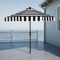In a room | open black and white striped umbrella on a cool coastal veranda with sea beyond the railing