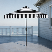 In a room | open black and white striped umbrella on a cool coastal veranda with sea beyond the railing