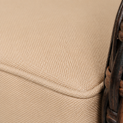 Fabric macro | solid beige cushion's fine basket weave and matching piped edge beside brown wicker