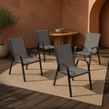 In a room | four Gray stacking armchairs in a terracotta courtyard room, with a plain oatmeal rug and wood table