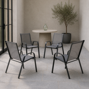 In a room | four Gray stacking armchairs on a cool limewash veranda, with blue-gray stone and a black-framed doorway
