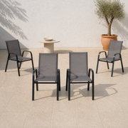 Four Gray stacking armchairs arranged together on a pale outdoor terrace