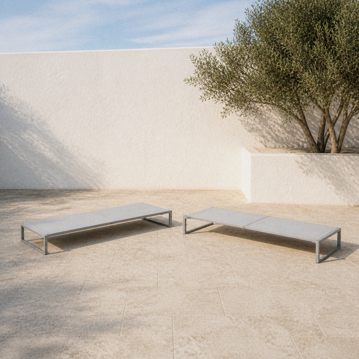 In a room | two flat pale-gray mesh chaise lounges on a limestone courtyard patio