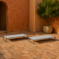 Angle | two flat pale-gray mesh chaise lounges on a terracotta garden loggia