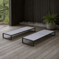 Room | two flat pale-gray mesh chaise lounges on a cedar deck beside a fern