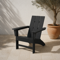Angle | black HDPE Adirondack chair at a three-quarter angle on a limestone terrace beside an olive planter