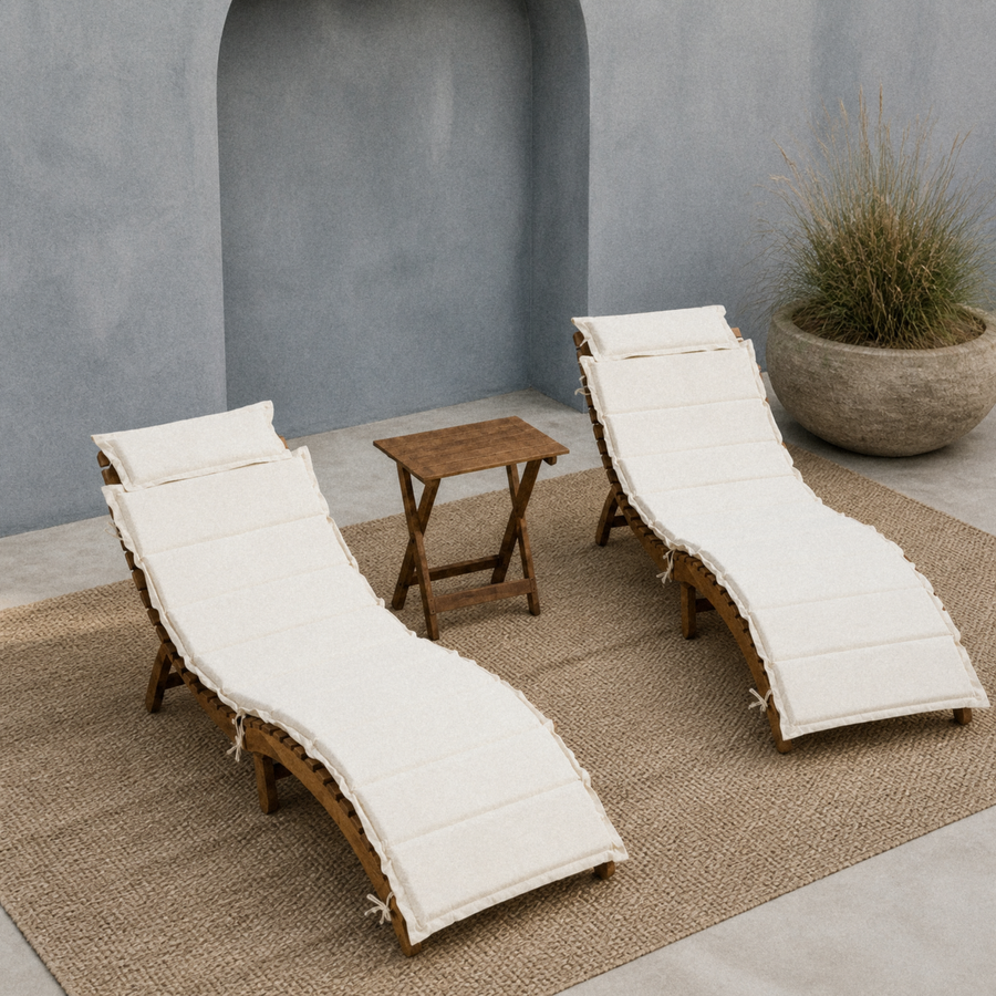 In a room | blue-gray courtyard with two ivory-cushioned acacia chaise lounges and a folding side table