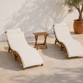 Terrace three-quarter view of two ivory-cushioned acacia chaise lounges and folding side table