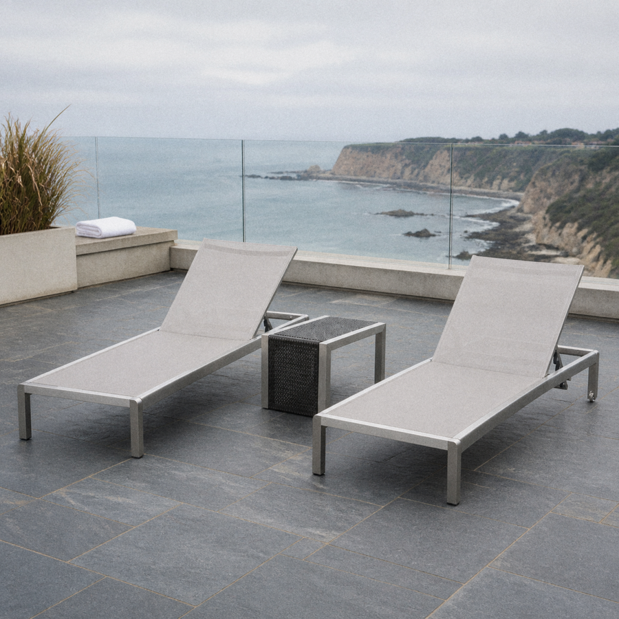 Coastal terrace | two light gray mesh chaise lounges and side table on blue-gray slate above the ocean