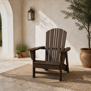Room 1 | one mahogany fan-back Adirondack chair on a limestone courtyard with pale plaster, an olive tree and a plain sand rug