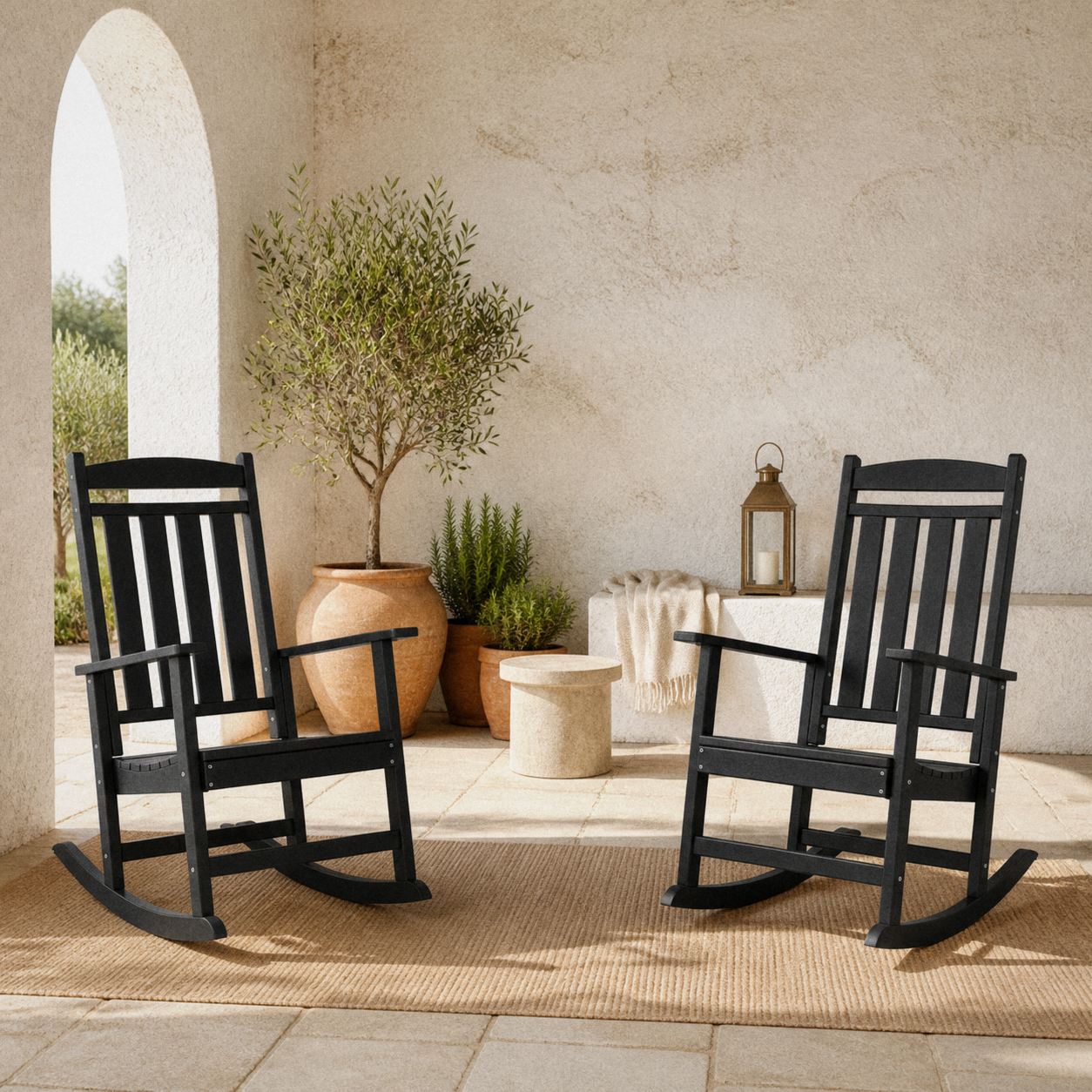 Courtyard | Two black rocking chairs on limestone pavers beside white stucco and planters