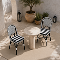 Elevated courtyard view of two black-and-white woven bistro dining chairs at a round stone table