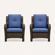Front | two matching blue-cushioned brown wicker patio chairs on a warm white studio sweep
