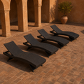 In a room | four dark brown woven folding chaise lounges in a terracotta courtyard