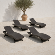 Four dark brown woven folding chaise lounges together on a limestone terrace