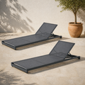 In a room | two gray mesh reclining chaise lounges on a sunlit limestone courtyard