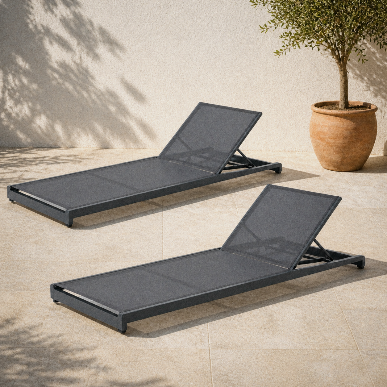 In a room | two gray mesh reclining chaise lounges on a sunlit limestone courtyard