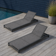 In a room | two gray mesh reclining chaise lounges beside a blue pool deck