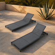 In a room | two gray mesh reclining chaise lounges against a clay garden wall with an agave