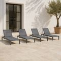 Scale | four dark charcoal mesh sling chaise lounges beside an uncropped full-height patio doorway